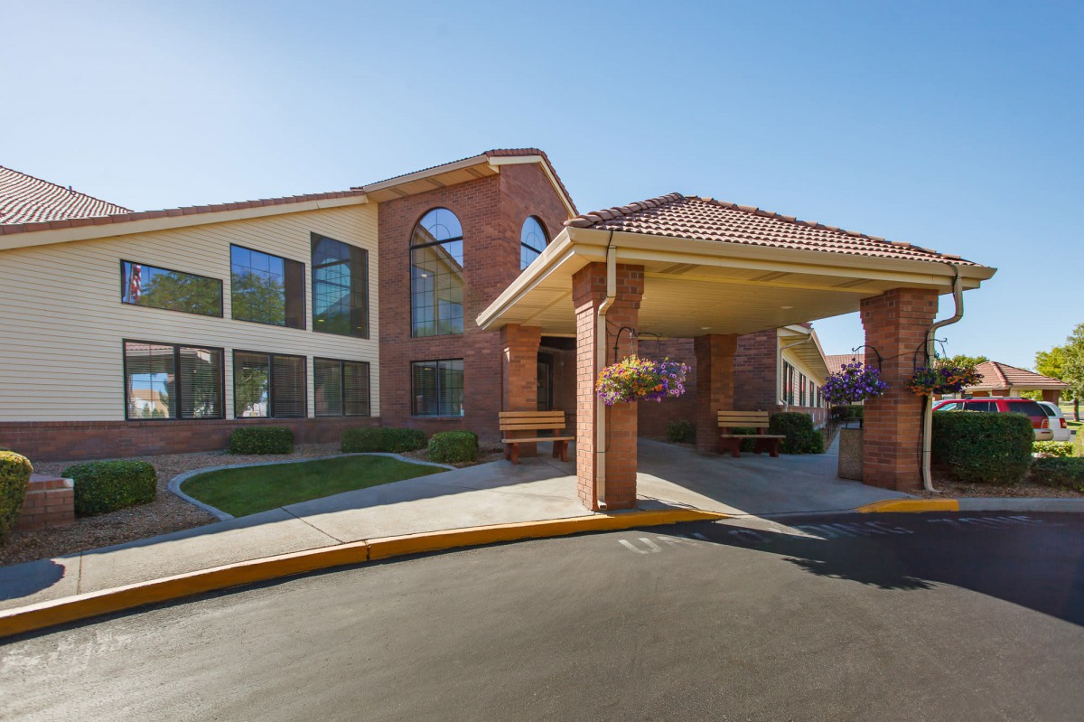 The image showcases a brick building with large windows and an entrance featuring a covered walkway.
