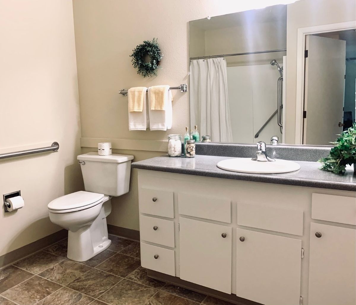 A clean and well-organized bathroom with a sink, toilet, and mirror.