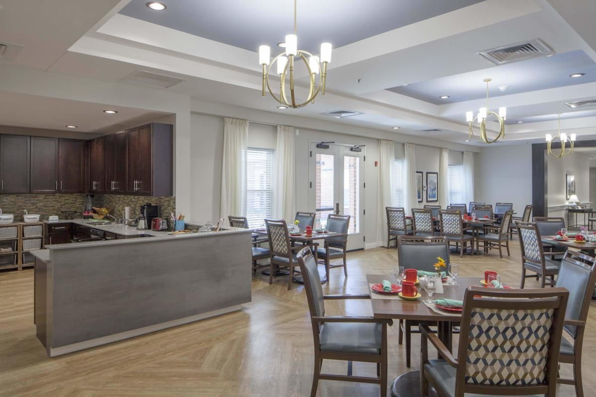 A spacious dining area with neatly arranged tables and chairs, illuminated by elegant chandeliers.
