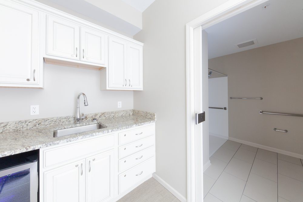 A modern, minimalist white kitchen with cabinets and a sink.