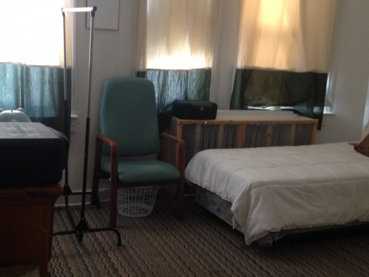 A cozy bedroom with a bed, a chair, and a standing lamp.