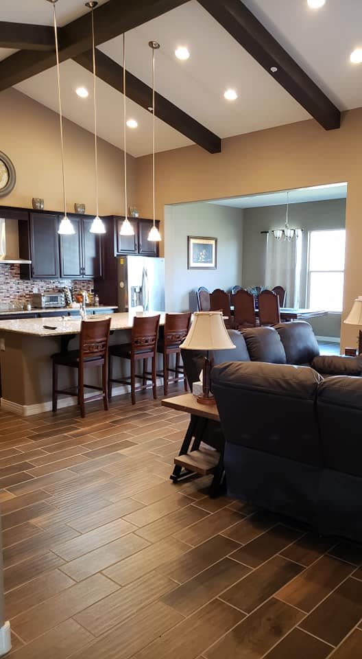 A modern open-concept living space featuring a kitchen with bar stools, a cozy living room, and a connected dining area.