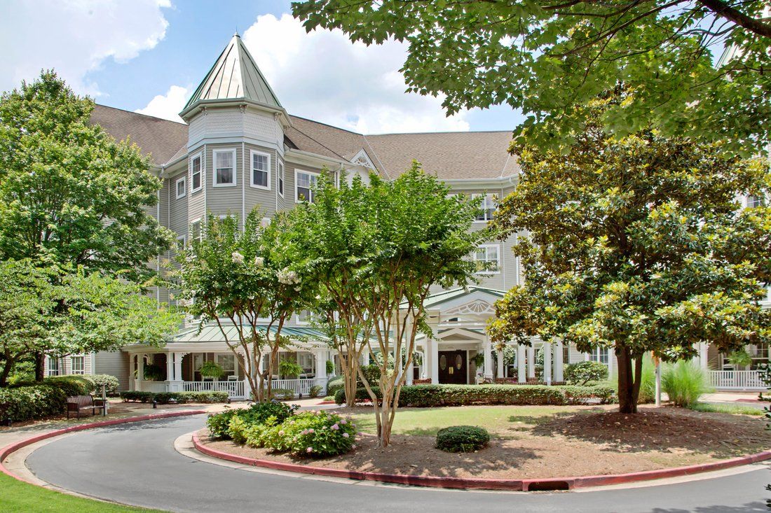 A beautiful building surrounded by lush greenery and trees on a sunny day.