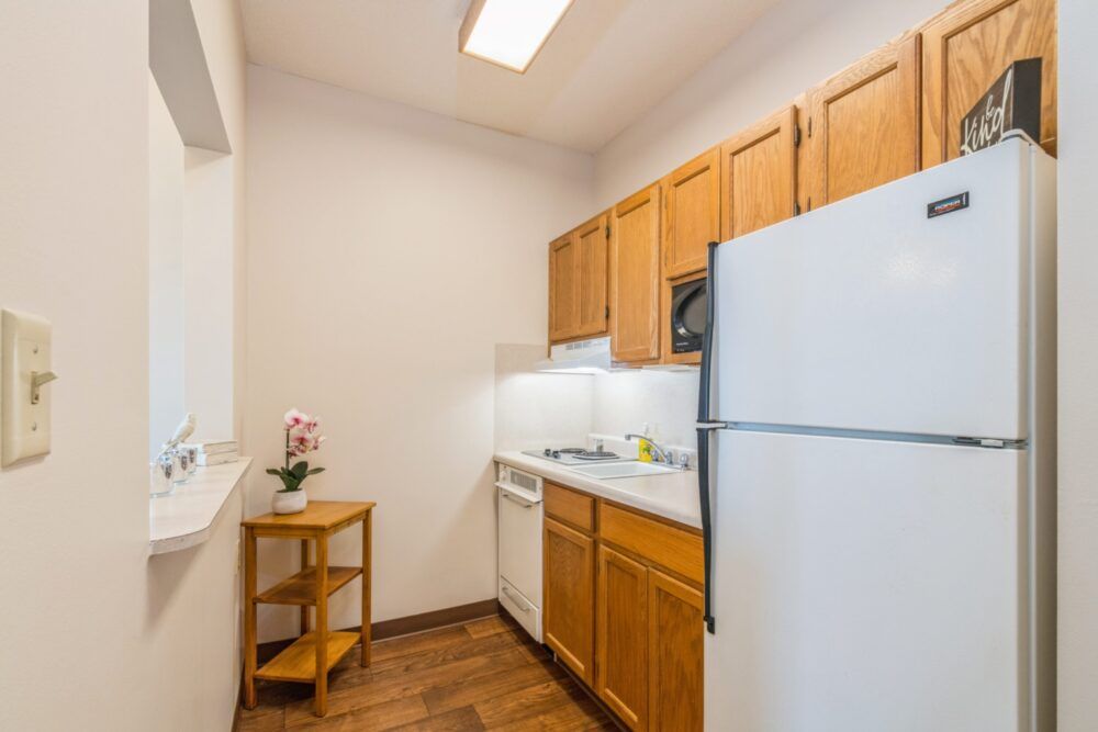 A compact kitchen with wooden cabinets, equipped with a refrigerator, stove, and dishwasher.