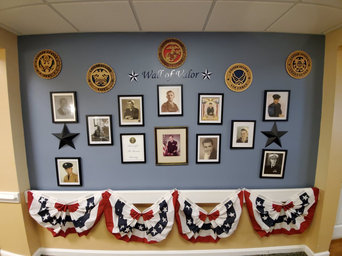 A decorated wall honoring military veterans with framed photographs and patriotic bunting.