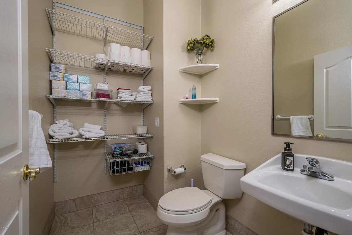 A well-organized bathroom featuring wall shelves stocked with toiletries and towels.