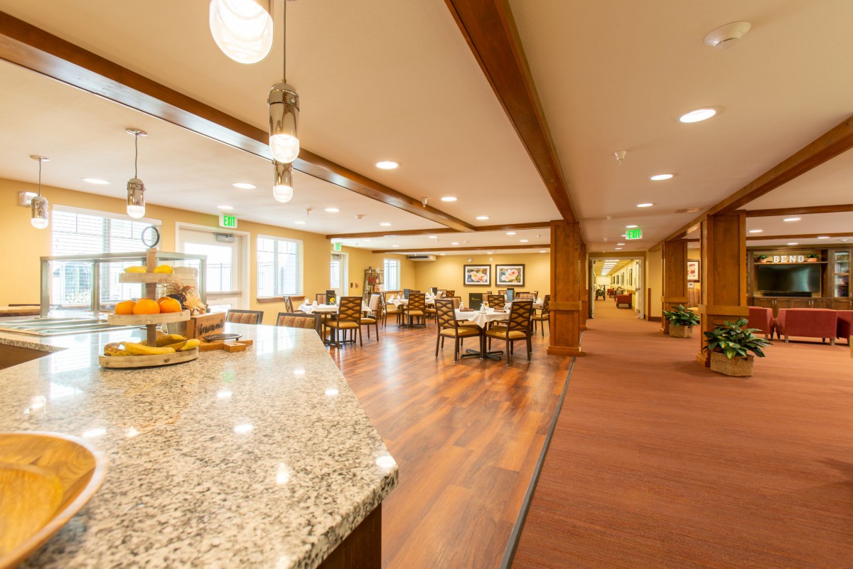 A warm and inviting dining area with wooden flooring, tables, chairs, and pendant lighting.