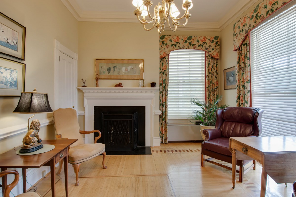 A traditional living room featuring a fireplace, elegant chandelier, and classic furniture.