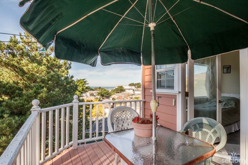 A cozy balcony with a glass table and umbrella, offering a scenic view.