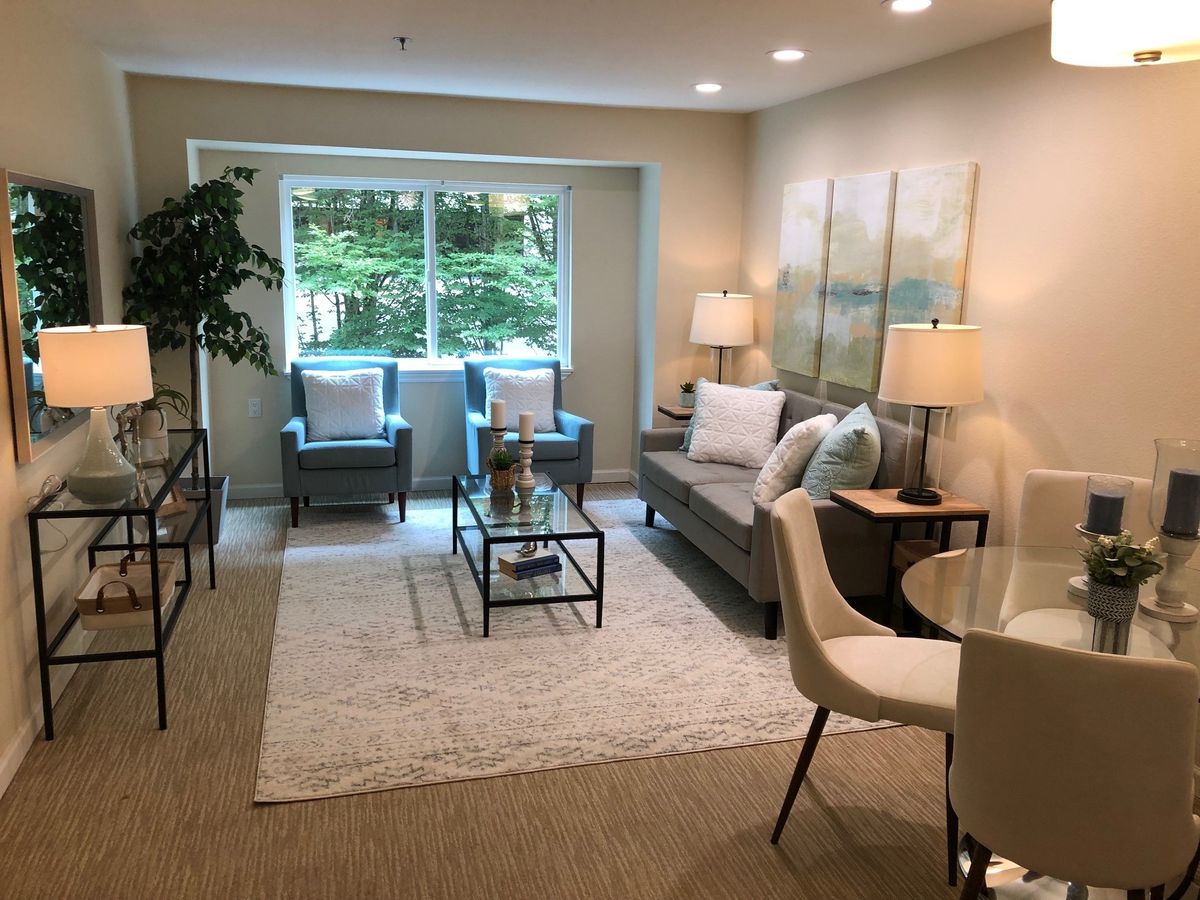 A cozy living room with modern decor, featuring a sofa, armchairs, and natural lighting.