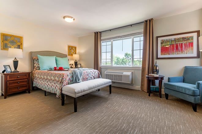 A well-decorated bedroom with a large window, colorful bedding, and stylish furnishings.