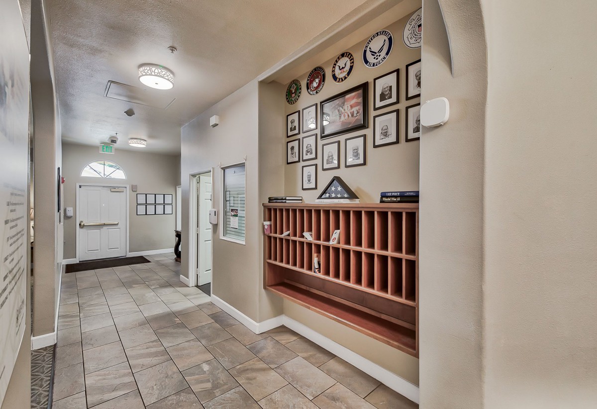 A hallway featuring framed pictures and a set of mail slots against a tiled floor.