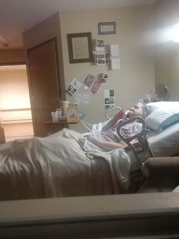 A patient resting in a hospital bed surrounded by medical equipment and personal items.