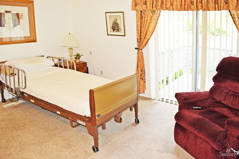 A bedroom with a hospital bed, curtains, and furniture.