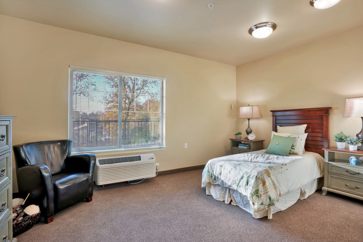 A minimalist bedroom with a single bed, chair, and large window.