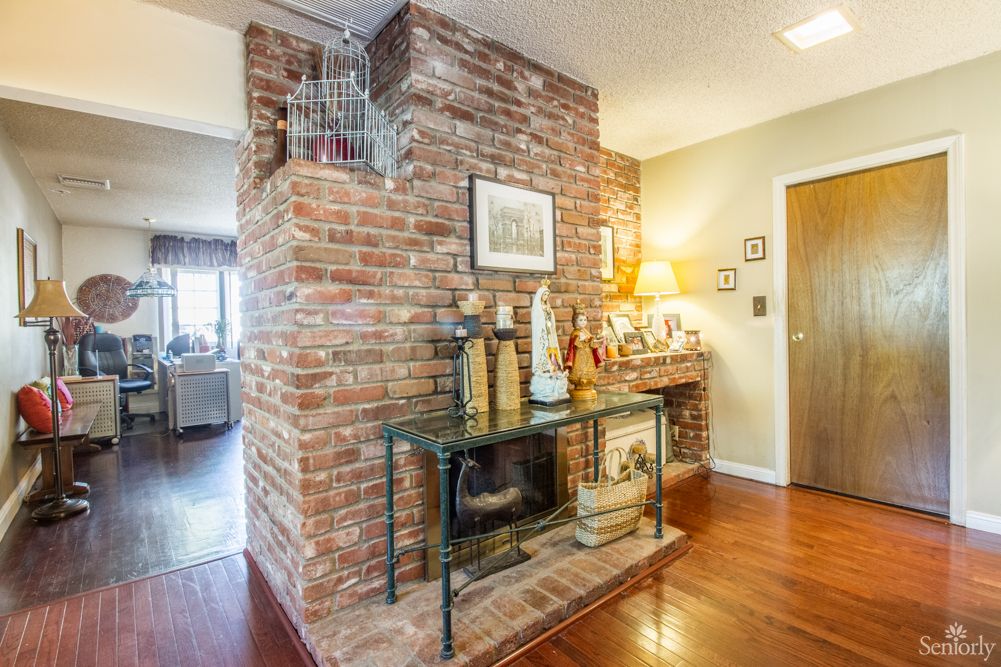 A cozy living space featuring a brick fireplace, a glass table, and warm wooden flooring.