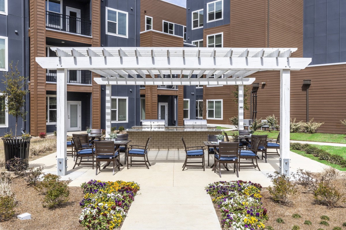 An outdoor patio area with a pergola and seating in an apartment complex.