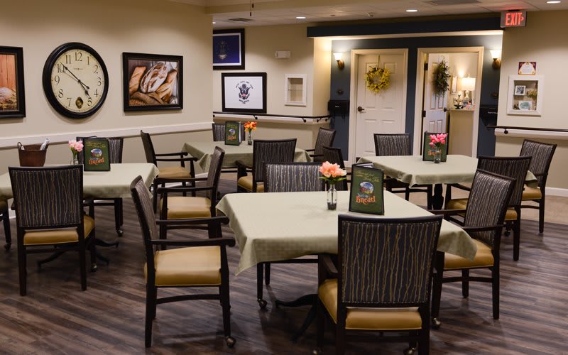 An indoor dining area with neatly arranged tables and chairs, decorated walls, and warm lighting.
