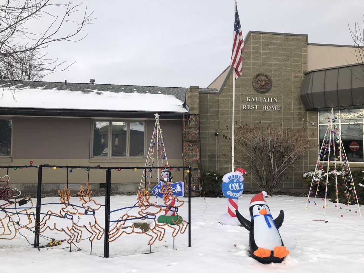 A snowy scene outside a town hall, featuring festive decorations including a penguin and candy canes, with an American flag waving nearby.