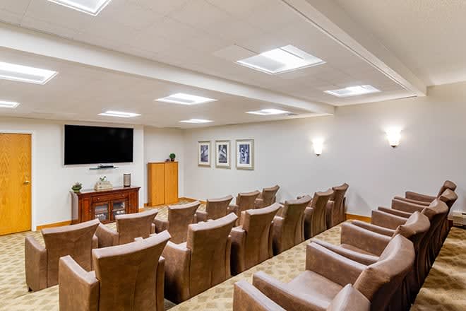 A well-designed home theater room with multiple rows of comfortable seating facing a large television screen.