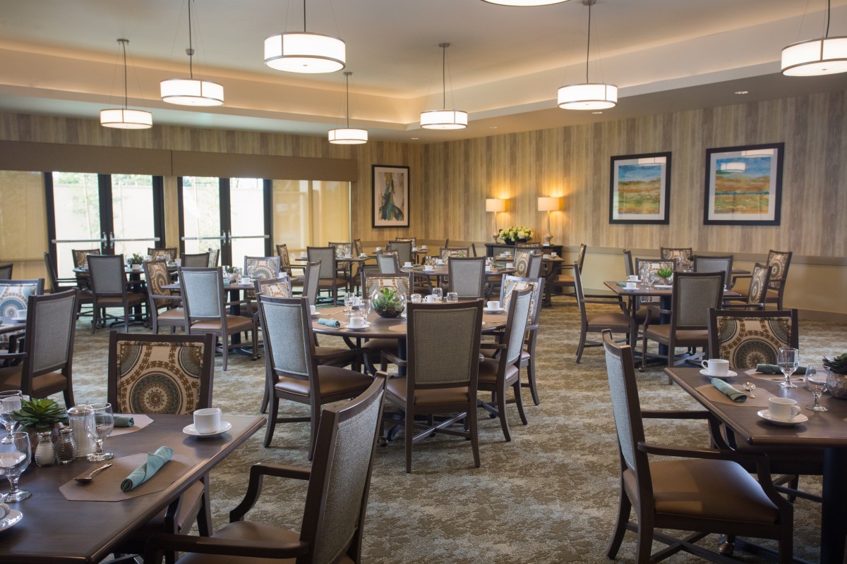 A spacious dining room with neatly arranged tables and chairs, elegant lighting, and tasteful decor.