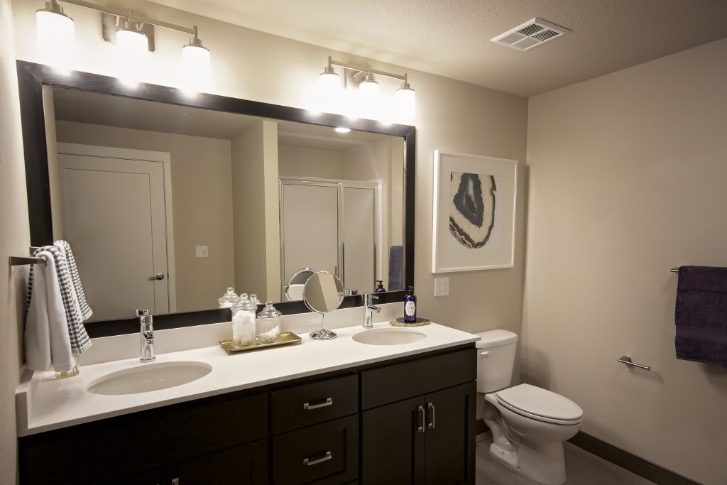 A modern bathroom with double sinks, a large mirror, and elegant lighting.