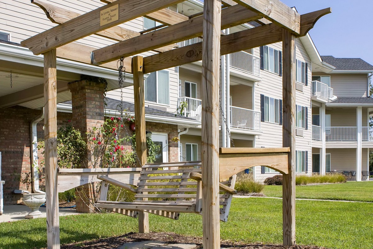 A wooden swing set in front of an apartment building.
