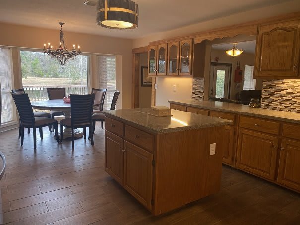 A spacious kitchen with an island and an adjacent dining area featuring a chandelier.