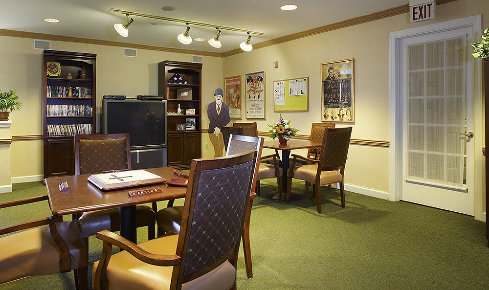 A cozy living room setup featuring a table with chairs and a shelving unit, decorated with artwork on the walls.