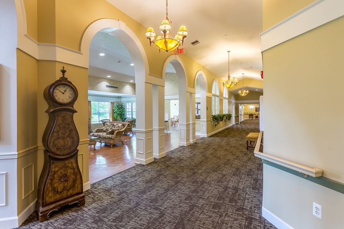 A well-lit hallway with elegant arches and a grandfather clock.
