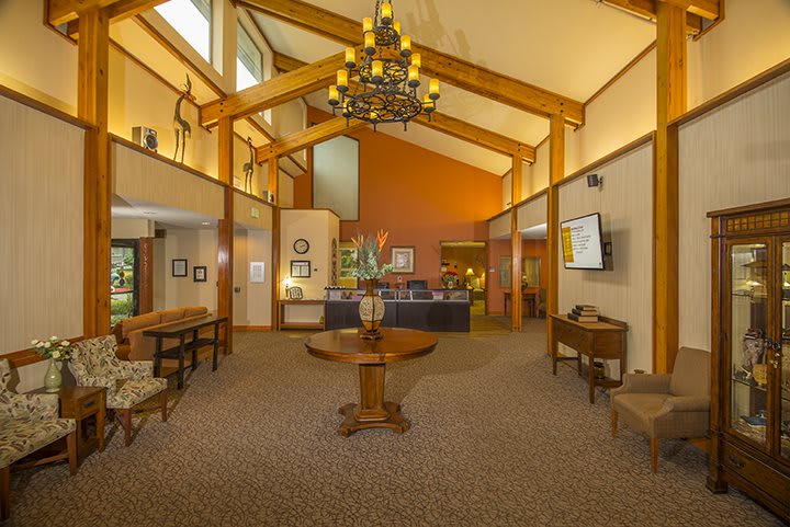 A warm and inviting hotel lobby with a chandelier, wooden beams, and reception desk.