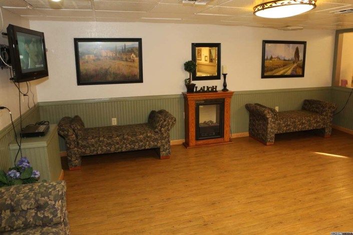 A cozy waiting area featuring two patterned benches, a decorative fireplace, and framed artwork on the walls.