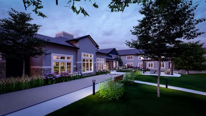 A modern building surrounded by a landscaped garden at dusk.