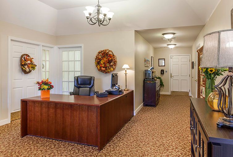A well-organized office reception area with a wooden desk and comfortable chairs, adorned with decorative items and warm lighting.