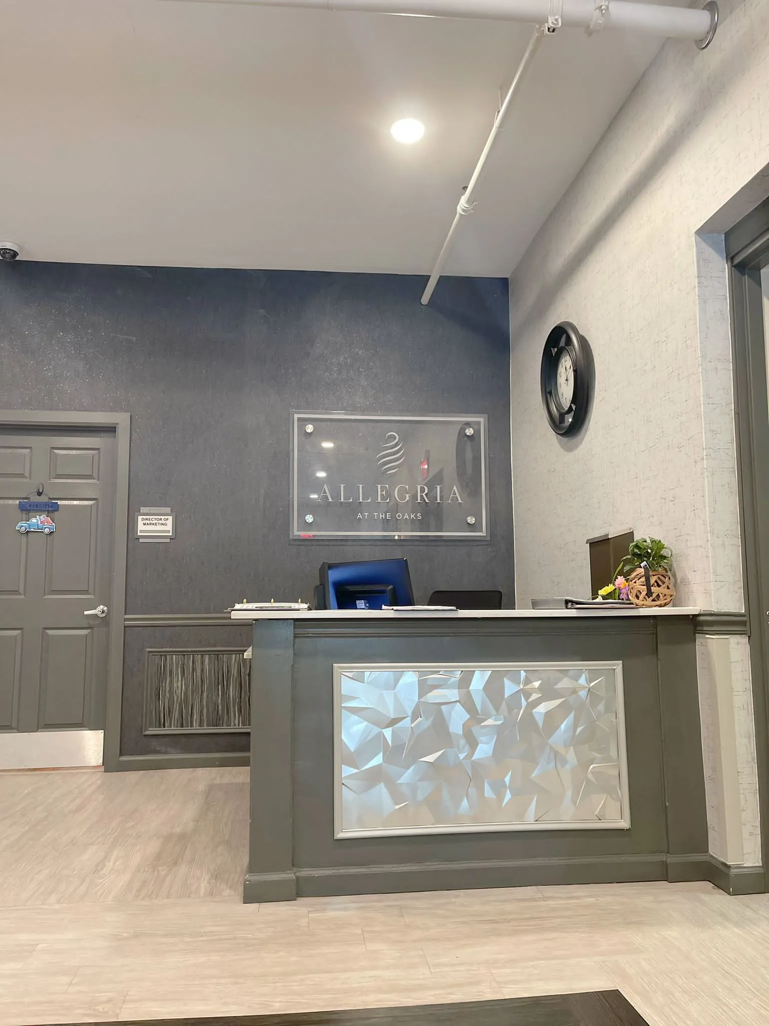 A modern reception area featuring a central desk with a wall clock and decorative elements.