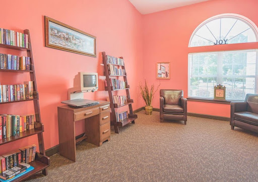 A cozy waiting area featuring vibrant pink walls, a computer desk, comfortable seating, and a magazine rack.