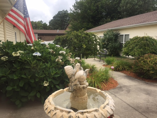 A beautifully landscaped garden featuring a decorative fountain and an American flag.