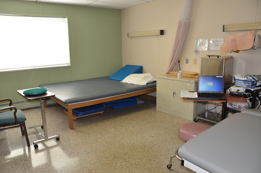 A hospital patient room equipped with a bed, medical equipment, and natural light from a nearby window.