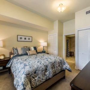 A cozy bedroom with a neatly made bed, bedside lamps, and a closet.