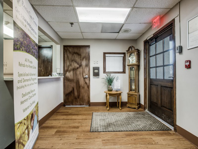 A cozy office lobby with wooden flooring, featuring a grandfather clock, a small table with an indoor plant, and a reception area.