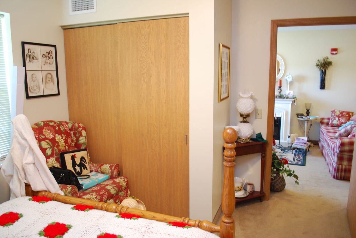 A cozy bedroom with a sliding closet door, armchair, and decorative lamp.