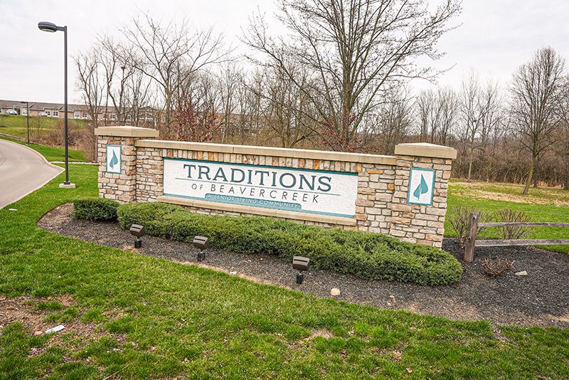 Entrance sign for Traditions of Beavercreek surrounded by greenery.