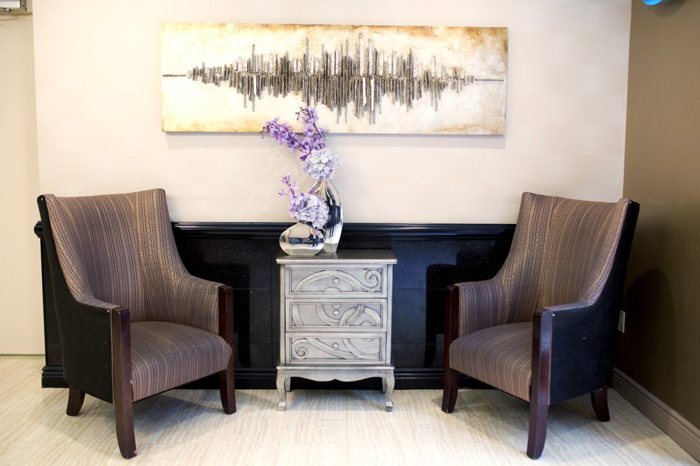 A cozy seating area with two chairs, a small decorative table, and wall art above.