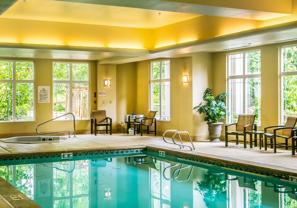 A serene indoor swimming pool area with large windows and cozy seating.