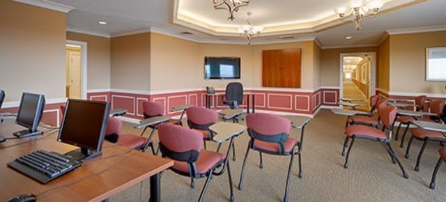 A conference room with chairs and tables arranged for a meeting, featuring a television and chandelier lighting.