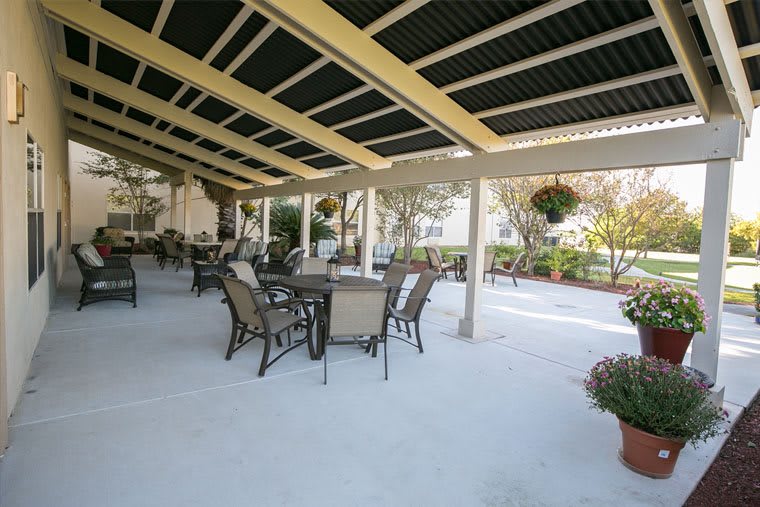 An outdoor patio with tables and chairs under a covered area.