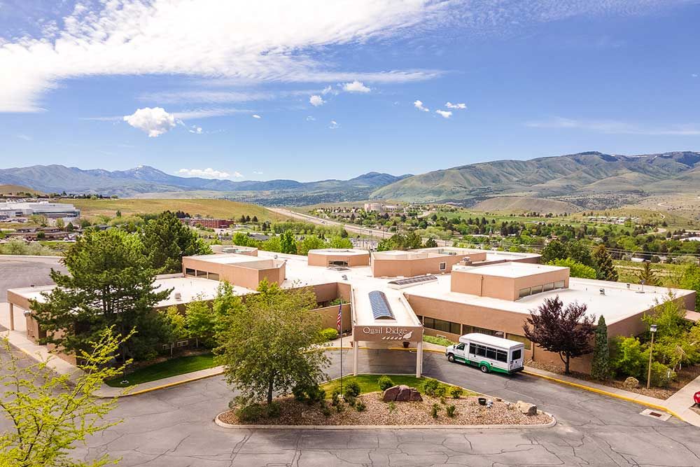 An aerial view of a school surrounded by mountains and greenery.