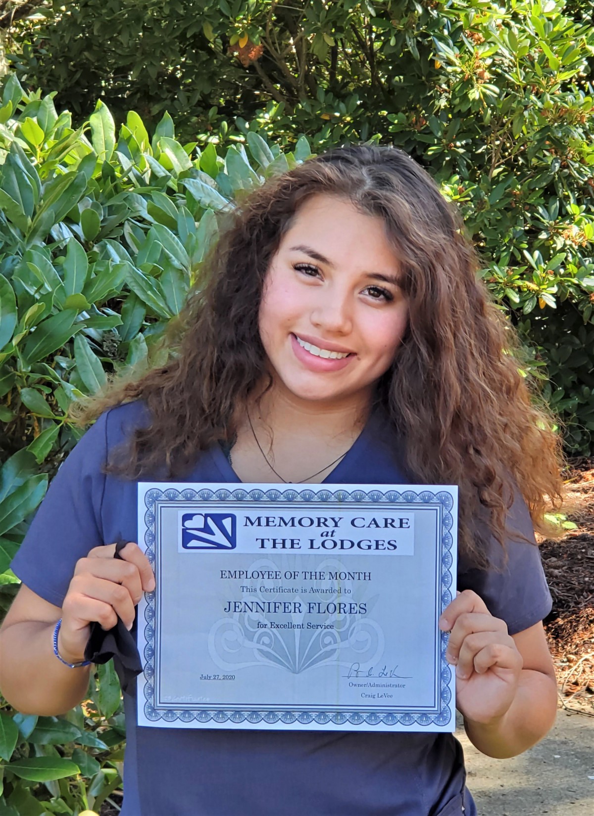 A person holding a certificate outdoors, smiling at the camera.