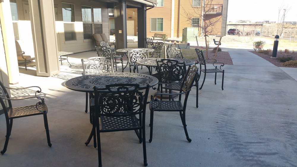 An outdoor patio area with metal tables and chairs basking in the sunlight.