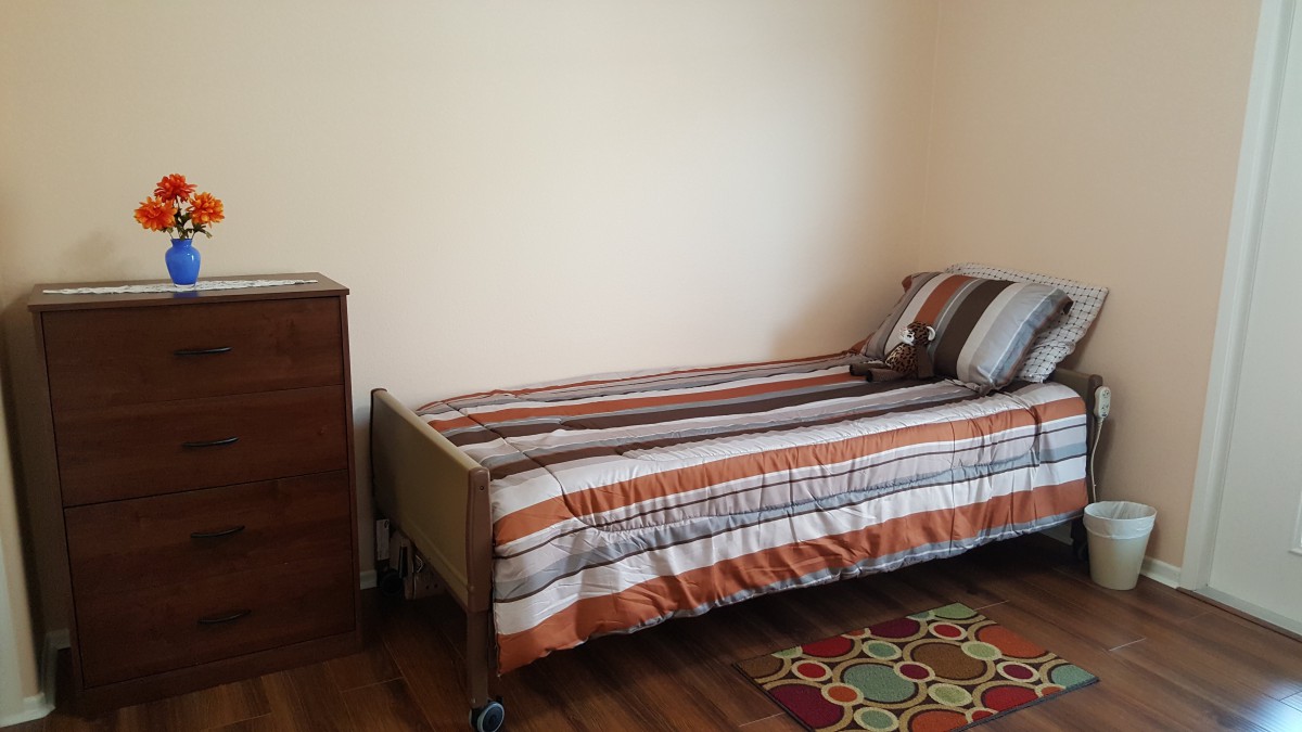 A minimalist bedroom with a single bed, striped bedding, and a small dresser.